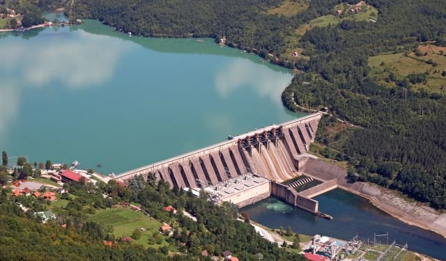 large dam surrounded on a river estuary by forests